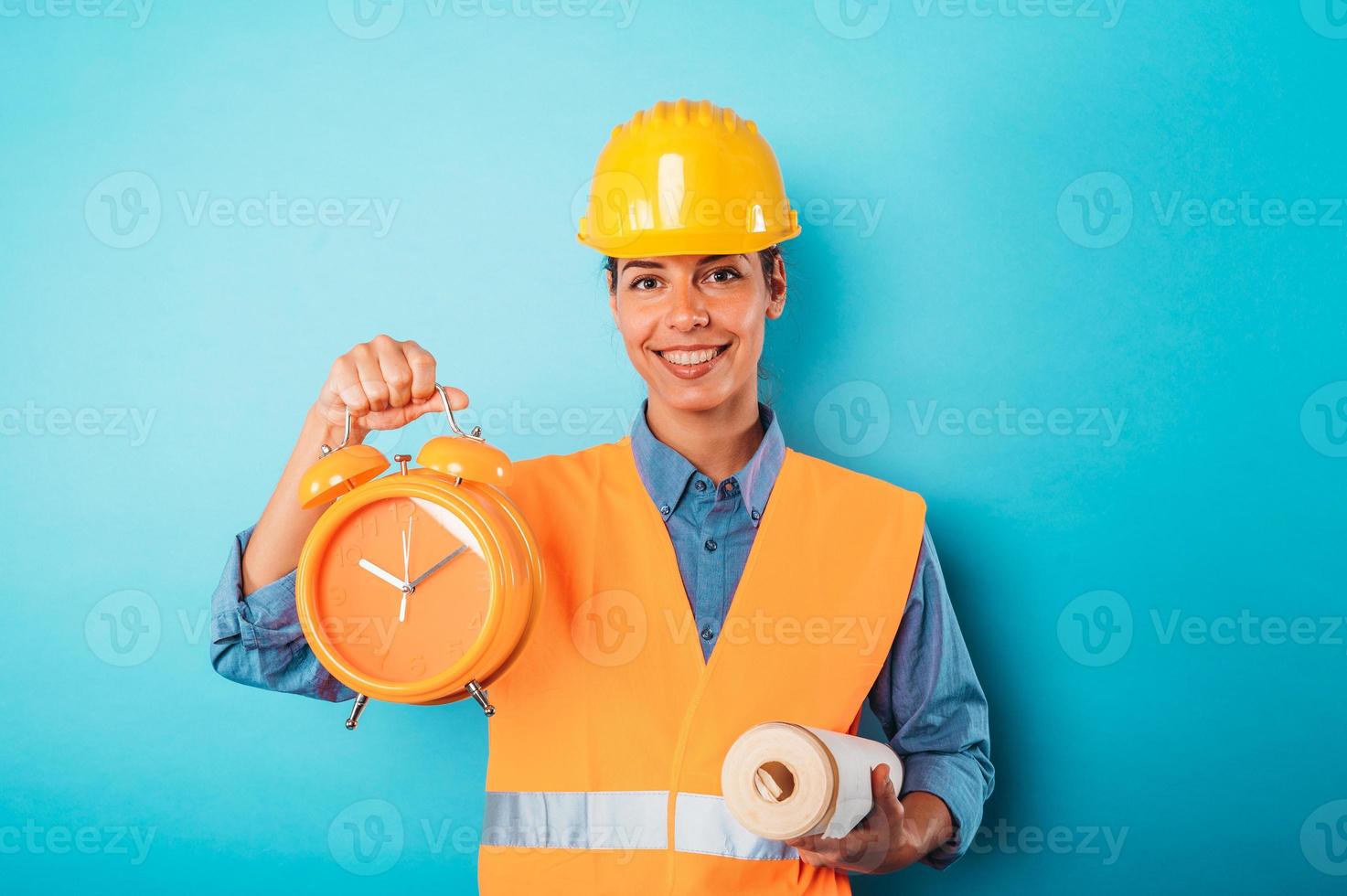 fiducioso donna architetto con un' casco e un sveglia foto