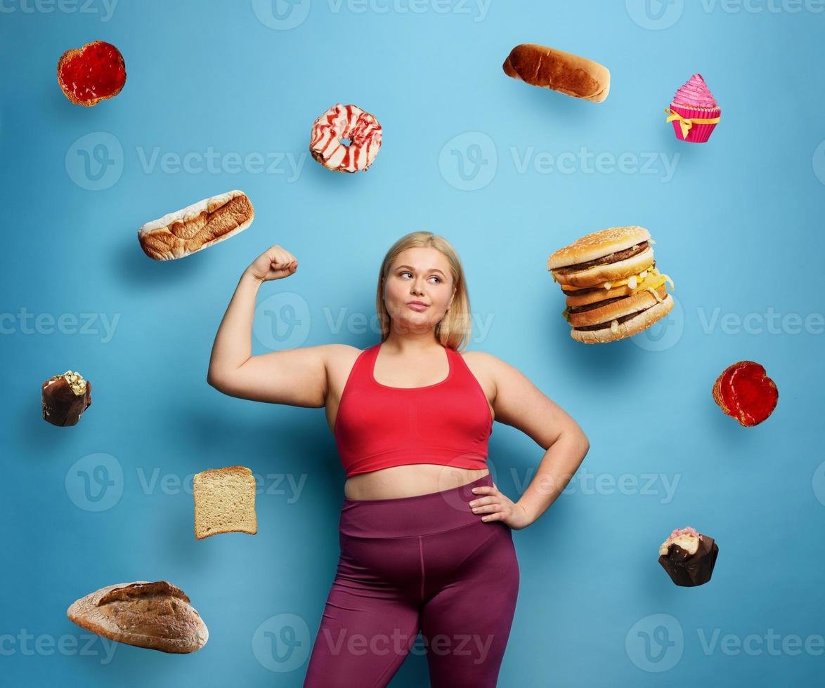 Grasso ragazza fa Palestra a casa. riflessivo espressione. ciano sfondo foto