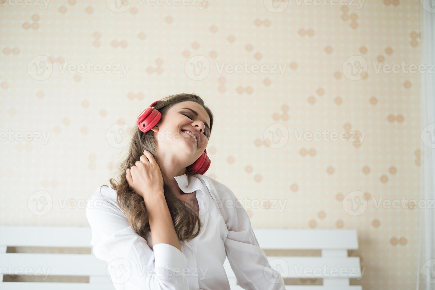 bella donna che ascolta musica al mattino seduta sul letto a casa foto