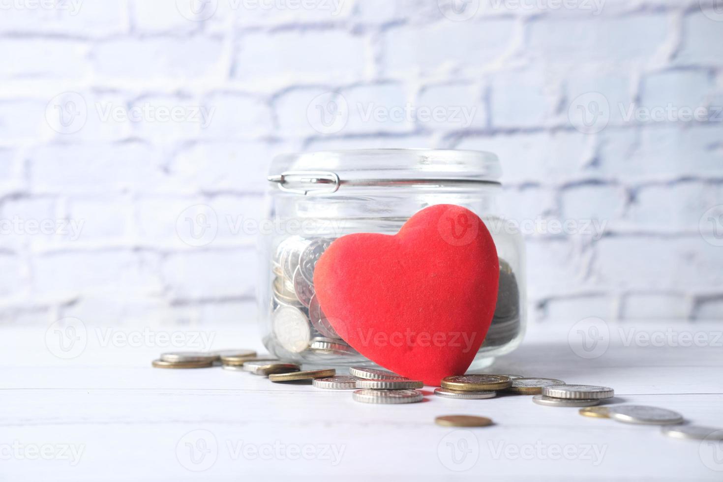 cuore rosso e monete in un barattolo foto