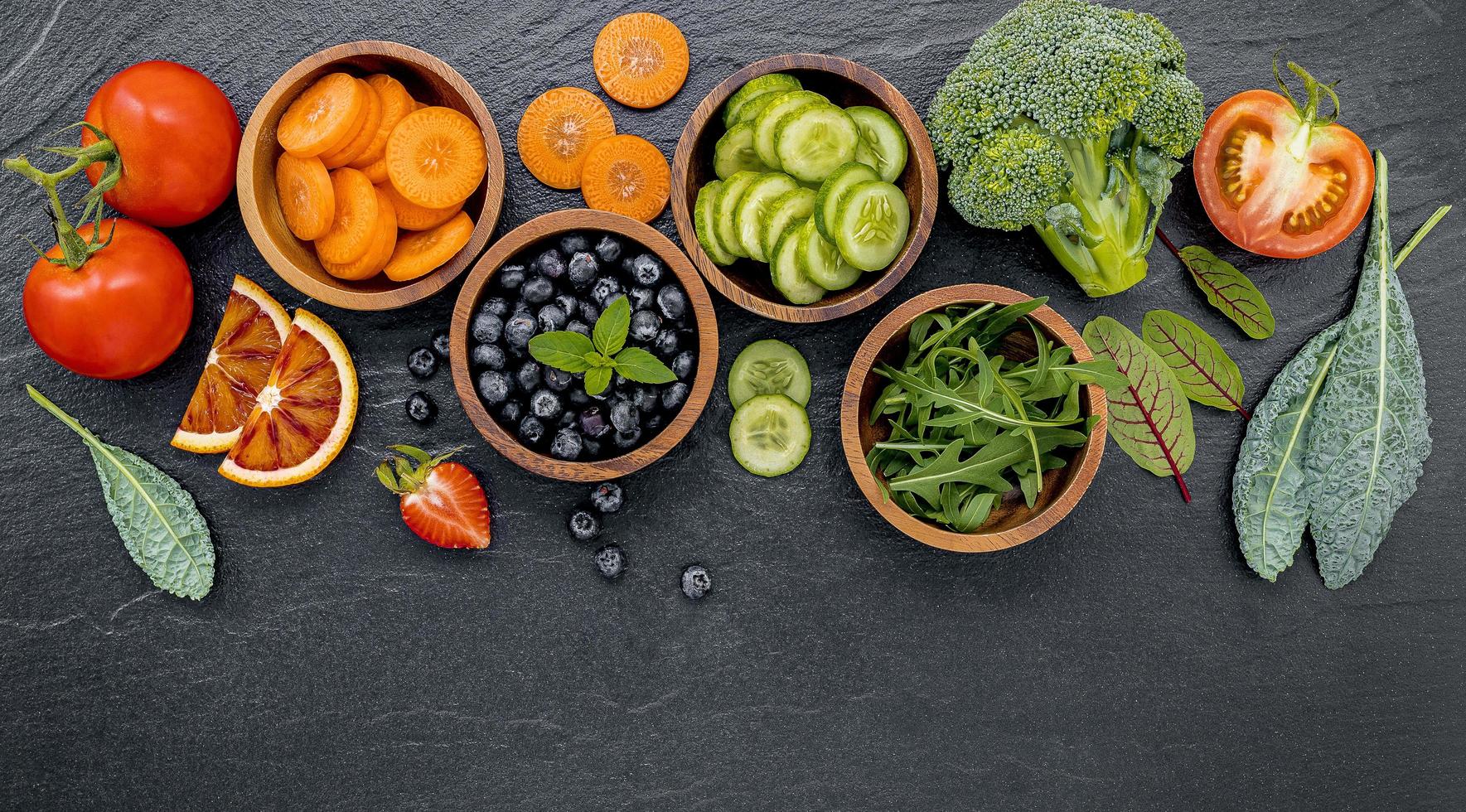 ciotole di frutta e verdura su uno sfondo scuro foto