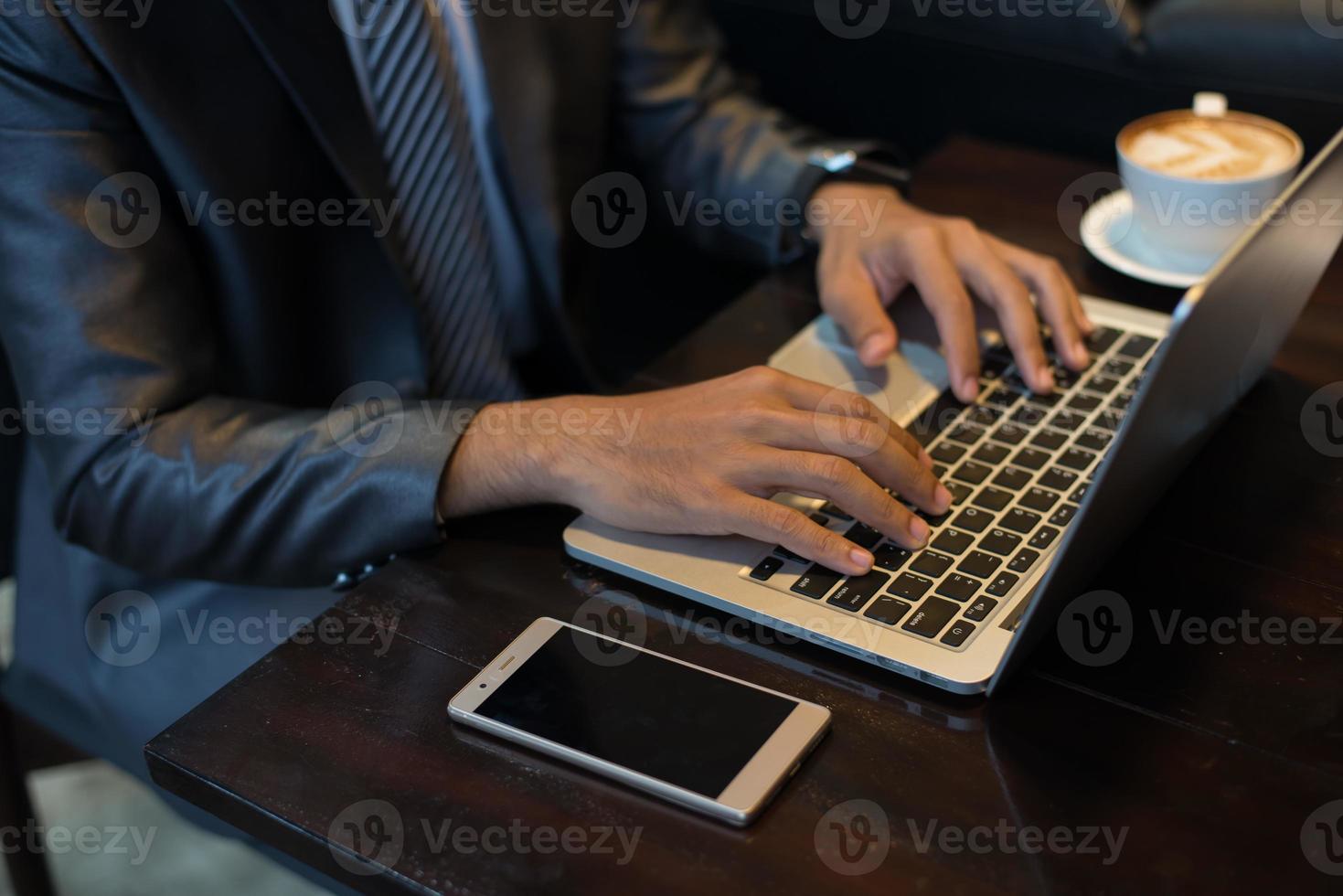 imprenditore digitando sulla tastiera del computer portatile sul posto di lavoro foto