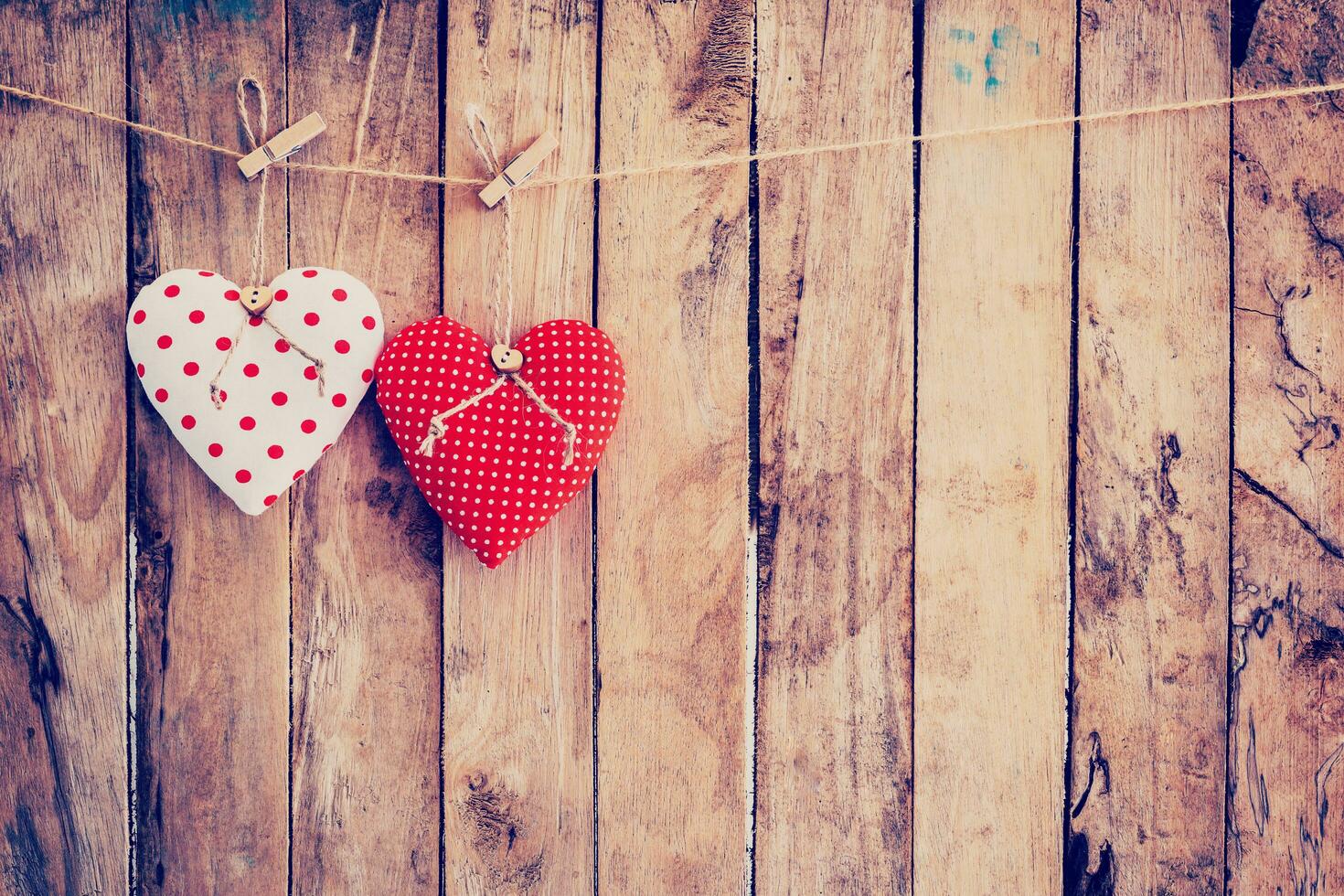 Due cuore tessuto sospeso su clothesline e legna sfondo con spazio. foto