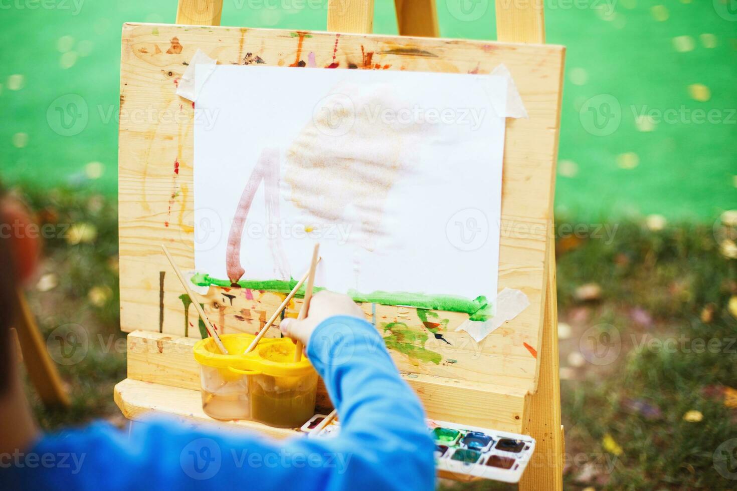 ragazzo disegna su il cavalletto. il bambino vernici foto