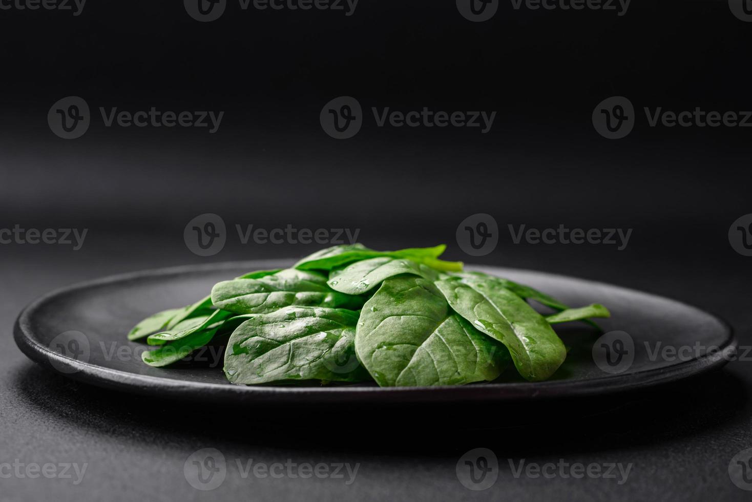 fresco verde spinaci le foglie su un' nero ceramica piatto foto