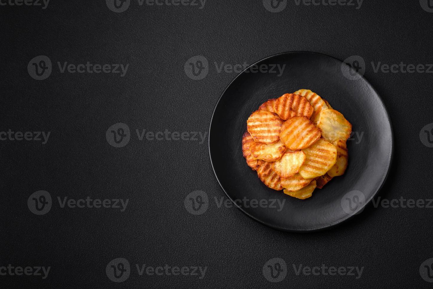 delizioso croccante fritte patate nel fette su un' nero ceramica piatto foto