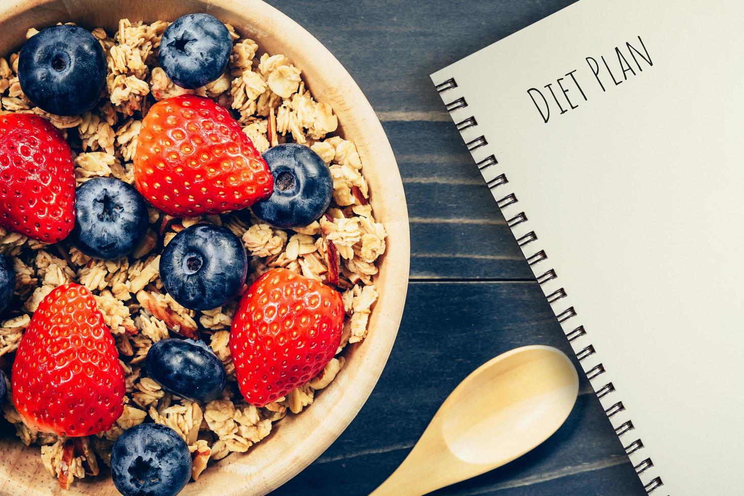 fatti in casa muesli e fresco frutti di bosco su legna tavolo con Nota libro e testo dieta Piano concetto, copia spazio. foto