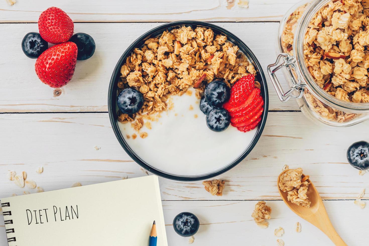 fatti in casa muesli e fresco frutti di bosco su legna tavolo con Nota libro e testo dieta Piano concetto, copia spazio. foto