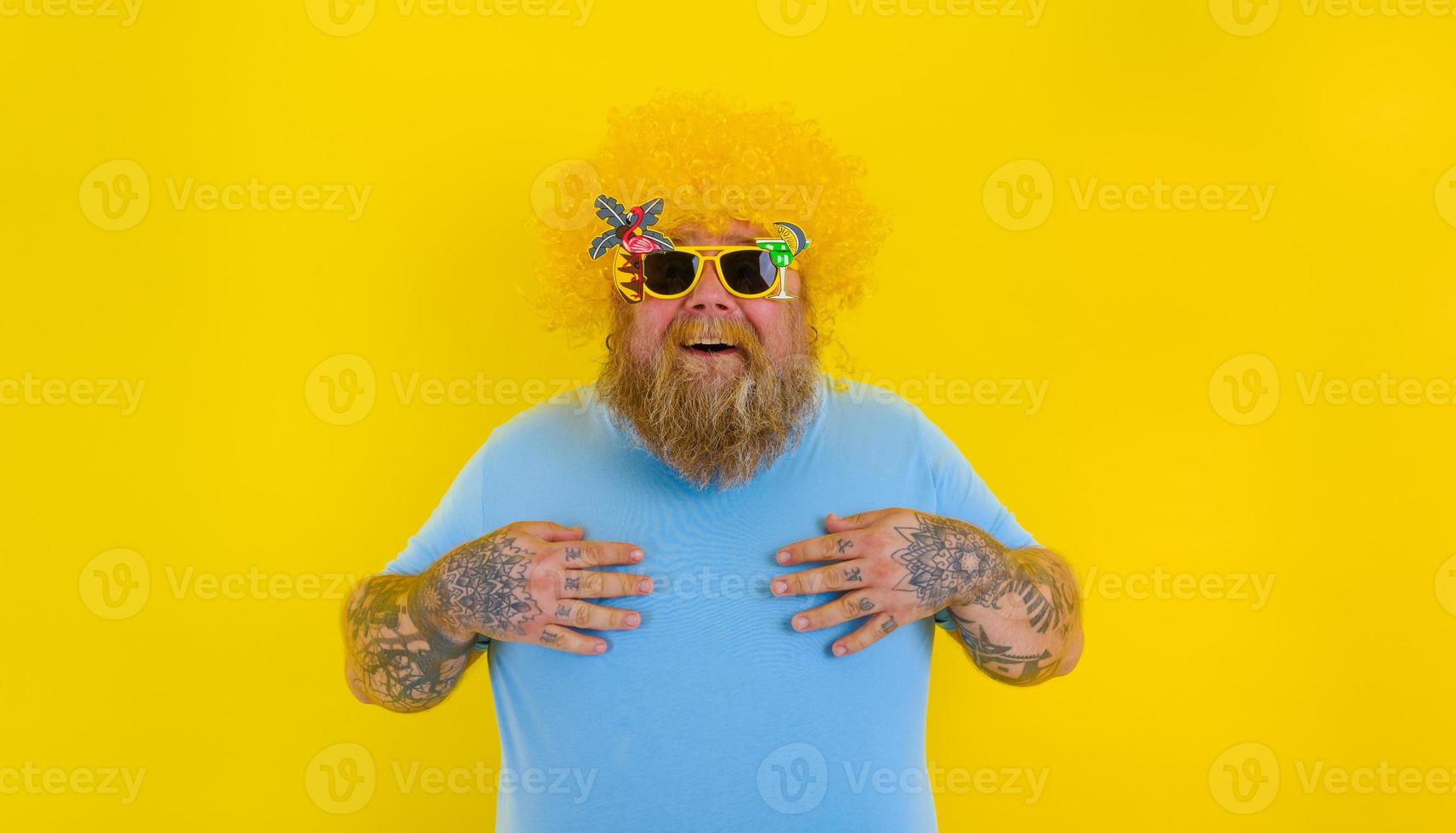 Grasso stupito uomo con parrucca nel testa e occhiali da sole foto