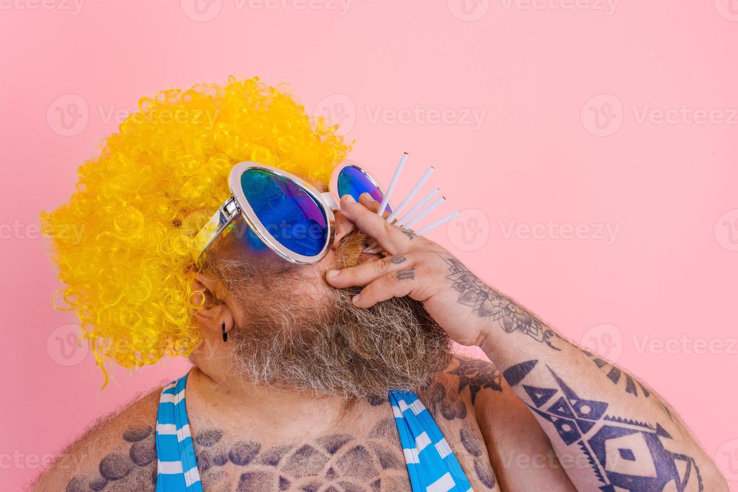 Grasso uomo con barba e parrucca fuma sigarette foto