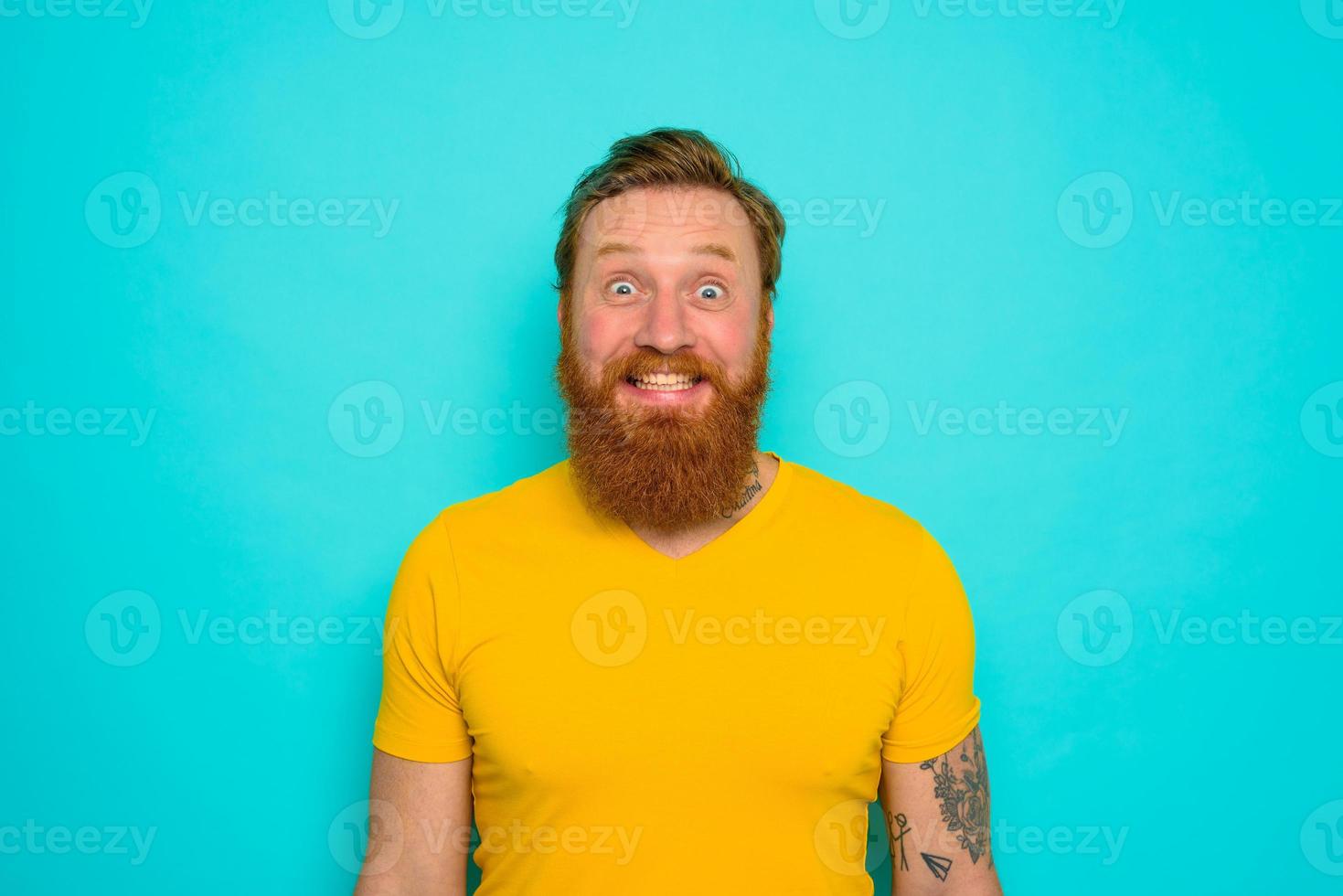 uomo con giallo maglietta e barba è molto contento foto