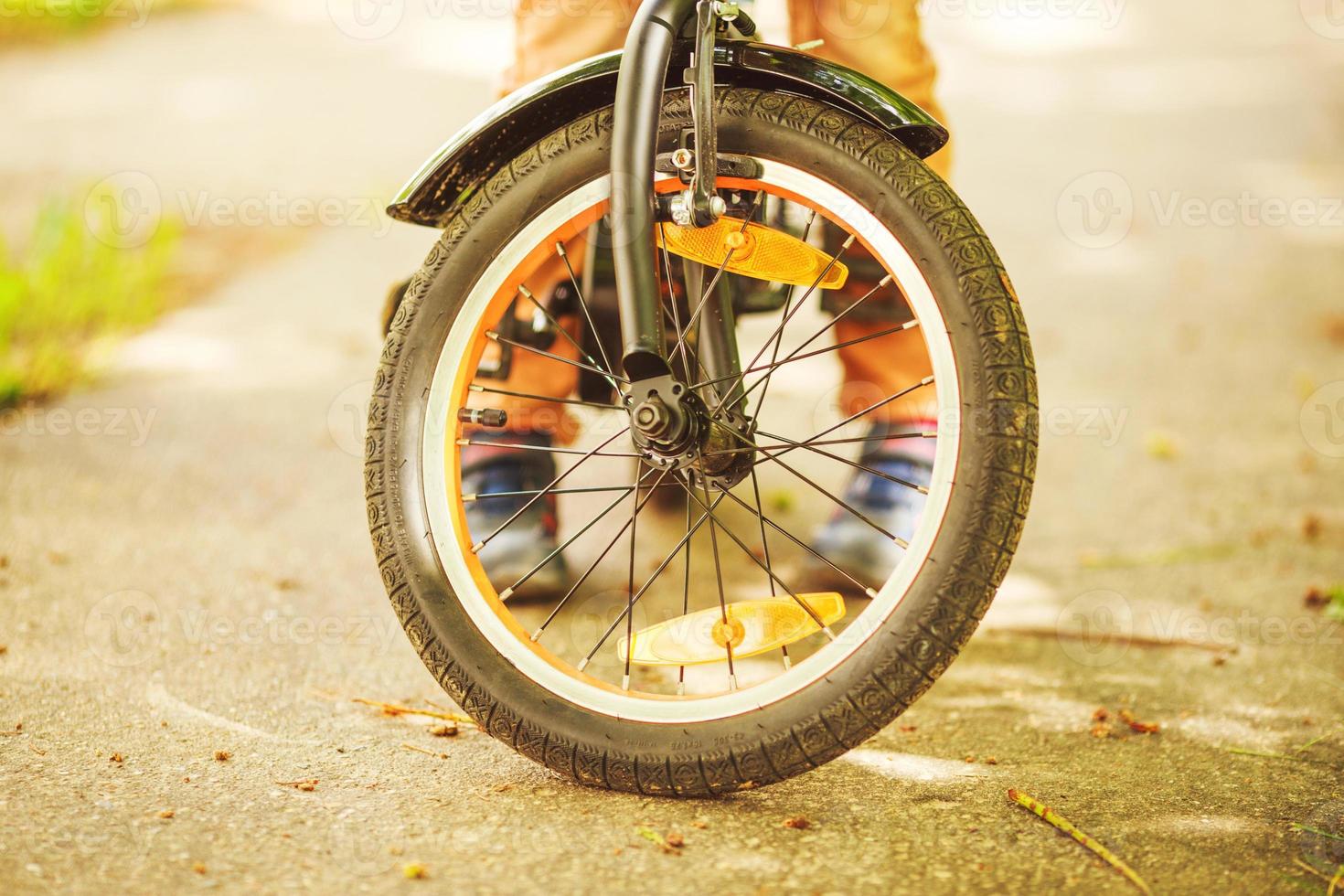 ragazzo con un' bicicletta su il strada. ruota di un' figli di bicicletta foto