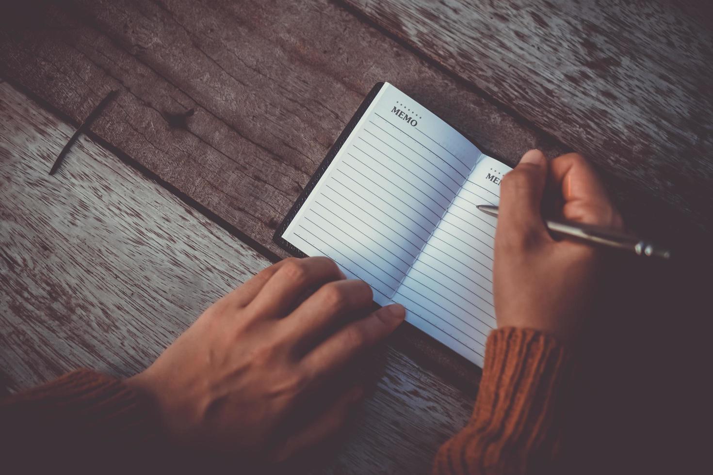 donna mano che scrive in un piccolo taccuino memo foto