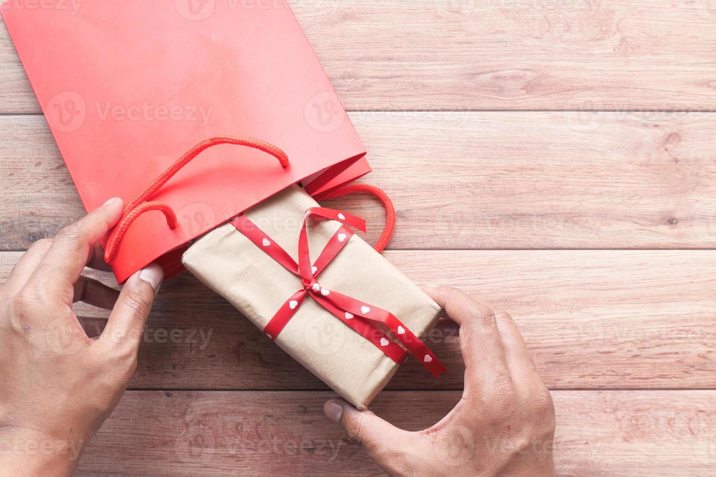 persona che mette un regalo in una borsa foto