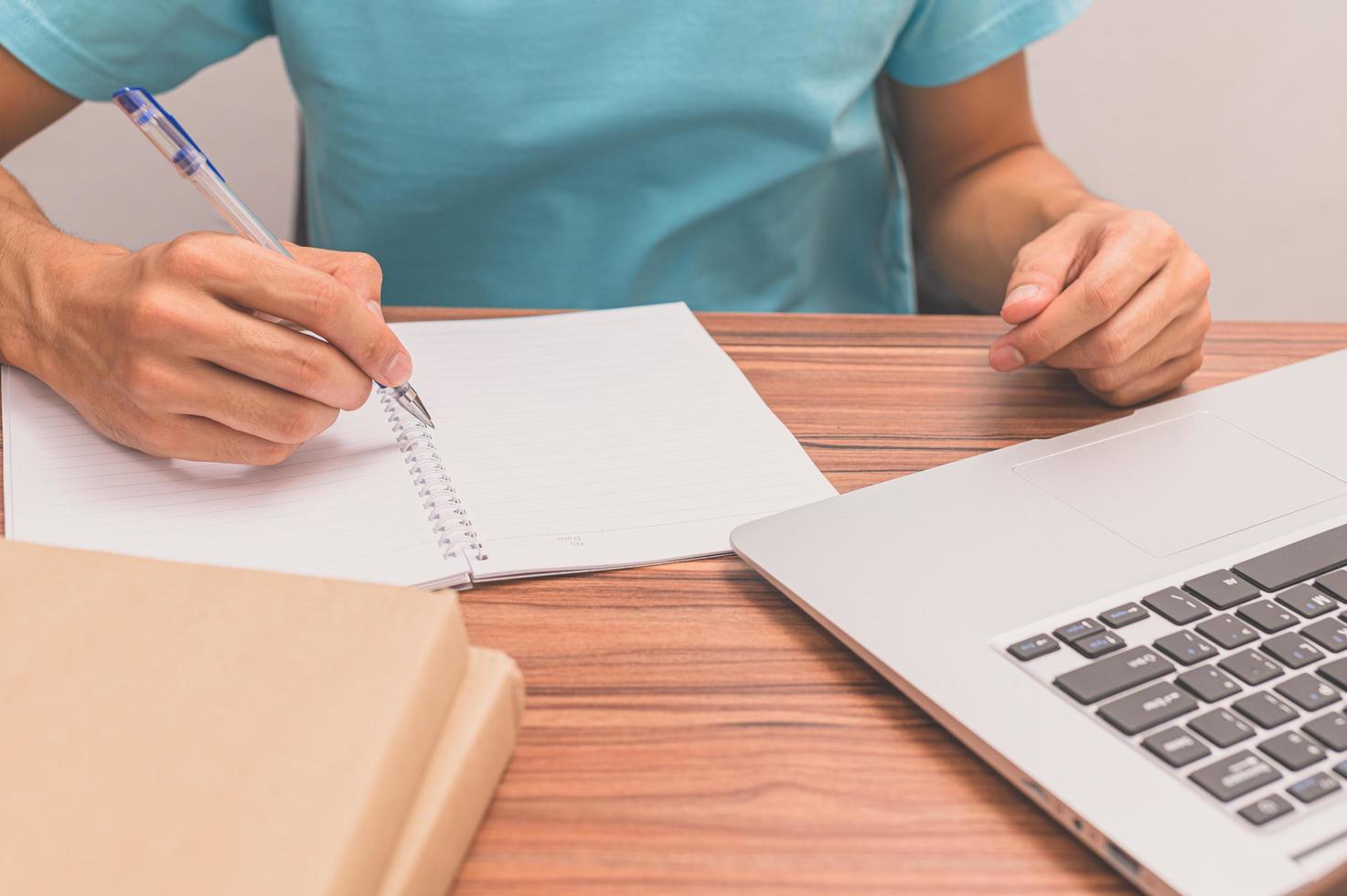 persona che scrive un libro a una scrivania foto