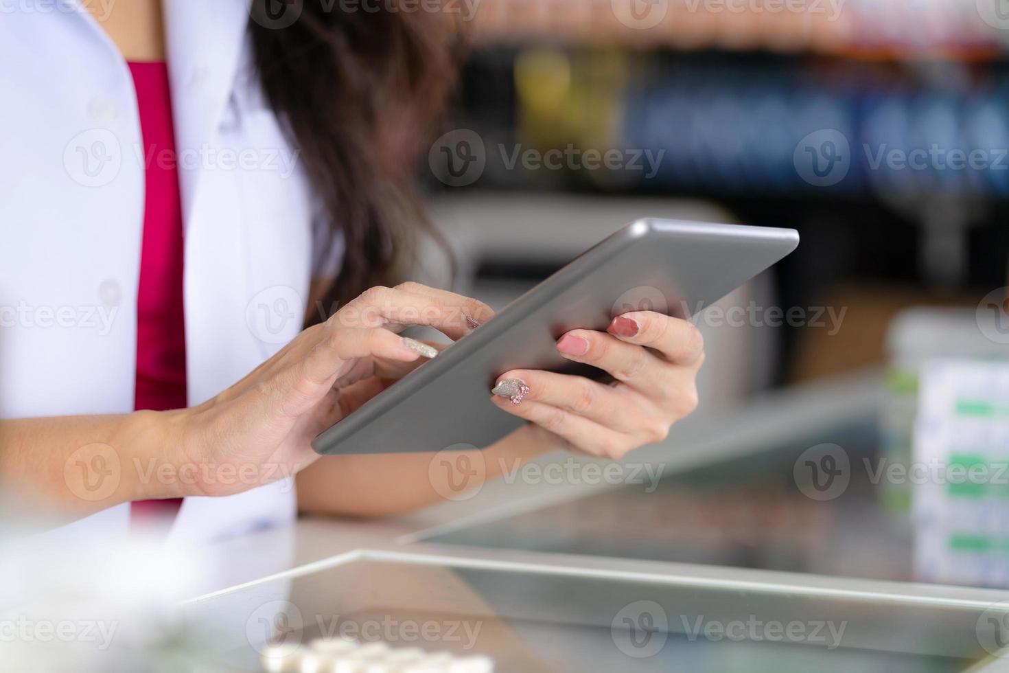 farmacista femminile utilizza la tavoletta digitale in farmacia foto