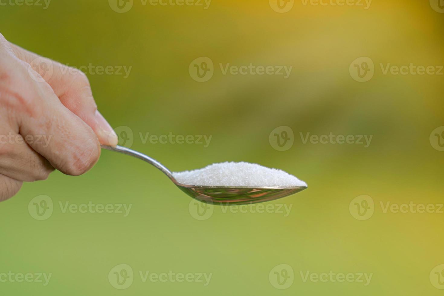 mano sta tenendo un cucchiaio con glutammato monosodico su uno sfondo naturale foto