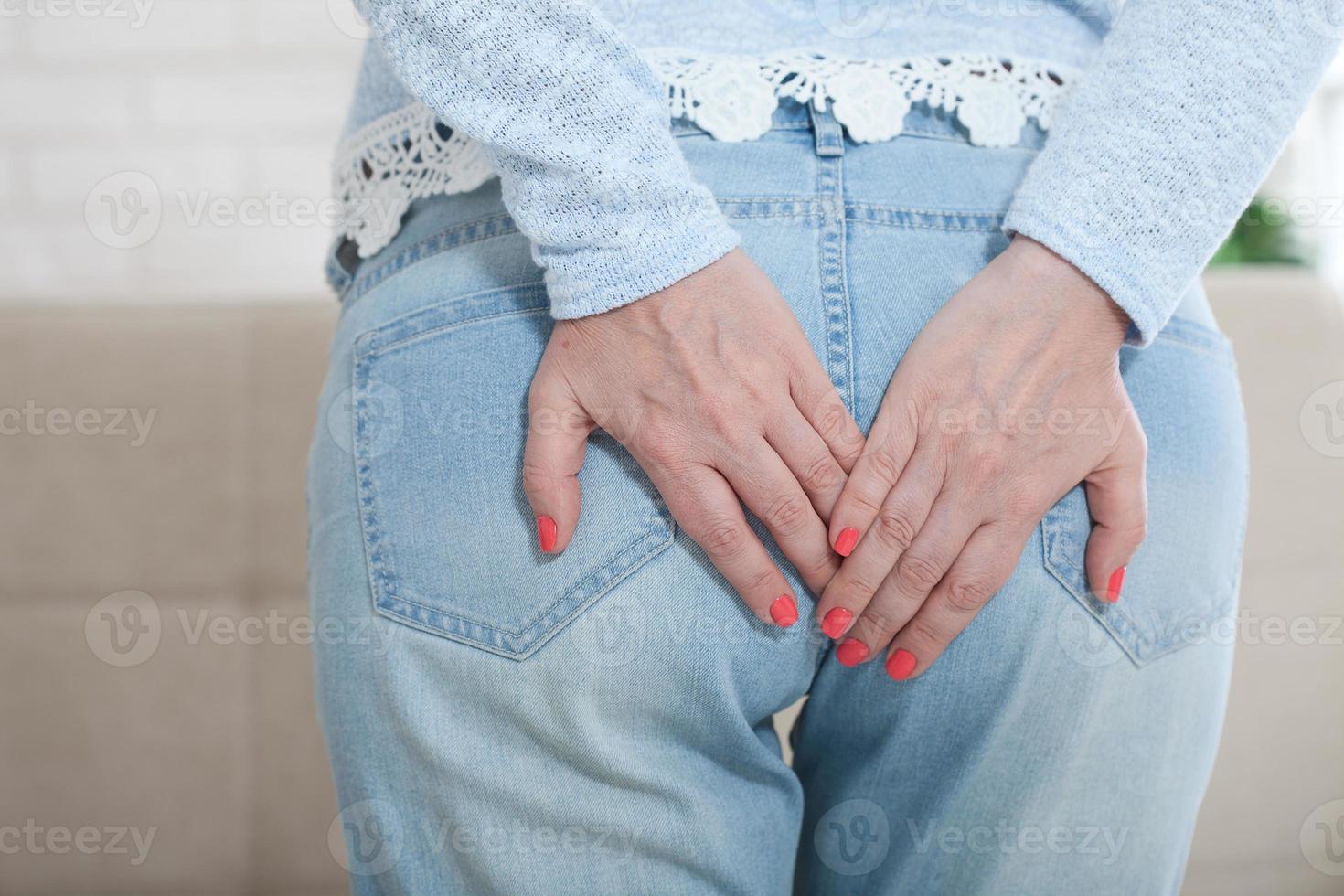 donna con emorroidi toccante sua germoglio con sua mani foto