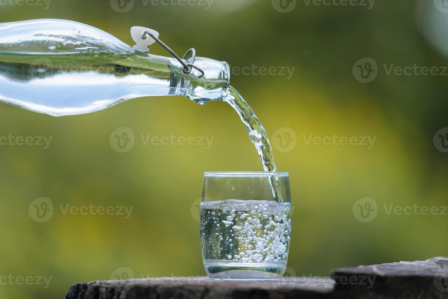 bottiglia di acqua potabile e vetro con sfondo naturale foto