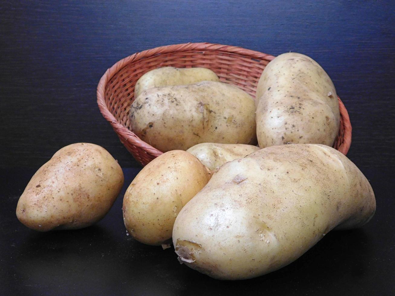 patate in un cesto di vimini su uno sfondo scuro foto