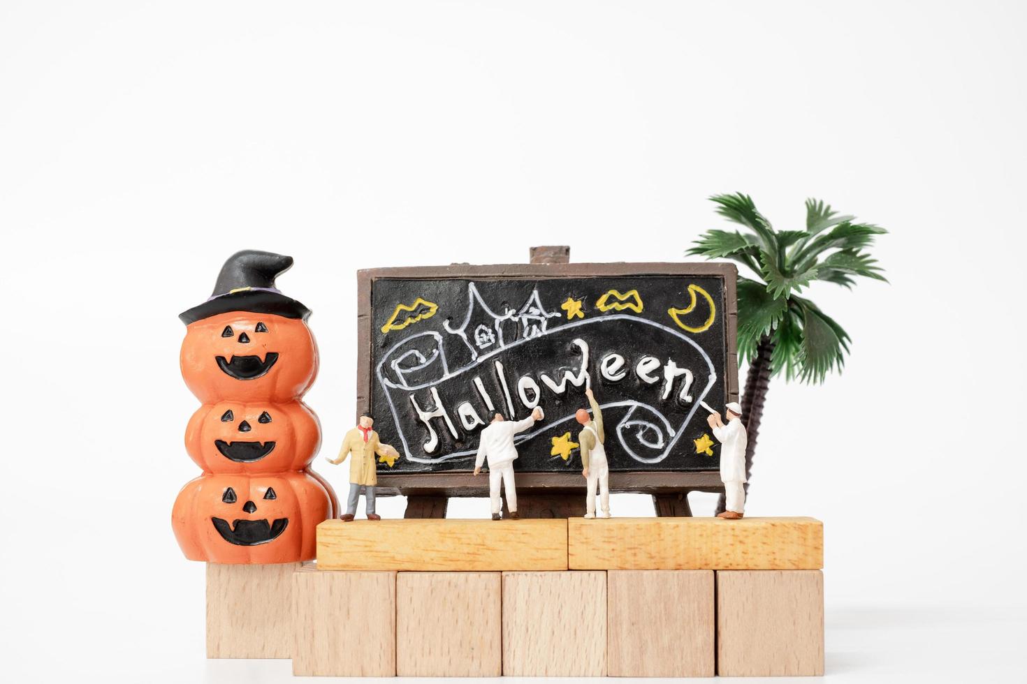 persone in miniatura che colorano le decorazioni del puntello del partito di Halloween su una priorità bassa bianca, concetto del partito di Halloween foto