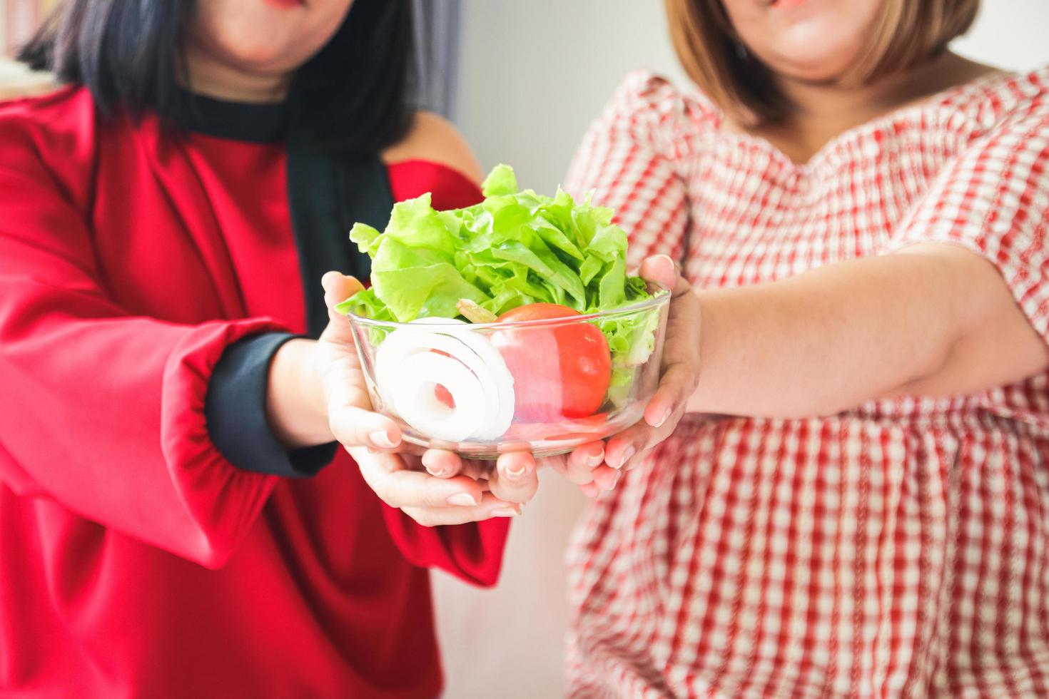 Due Grasso donne chi mangiò biologico insalata nel un' bicchiere tazza. obesità Salute concetto foto