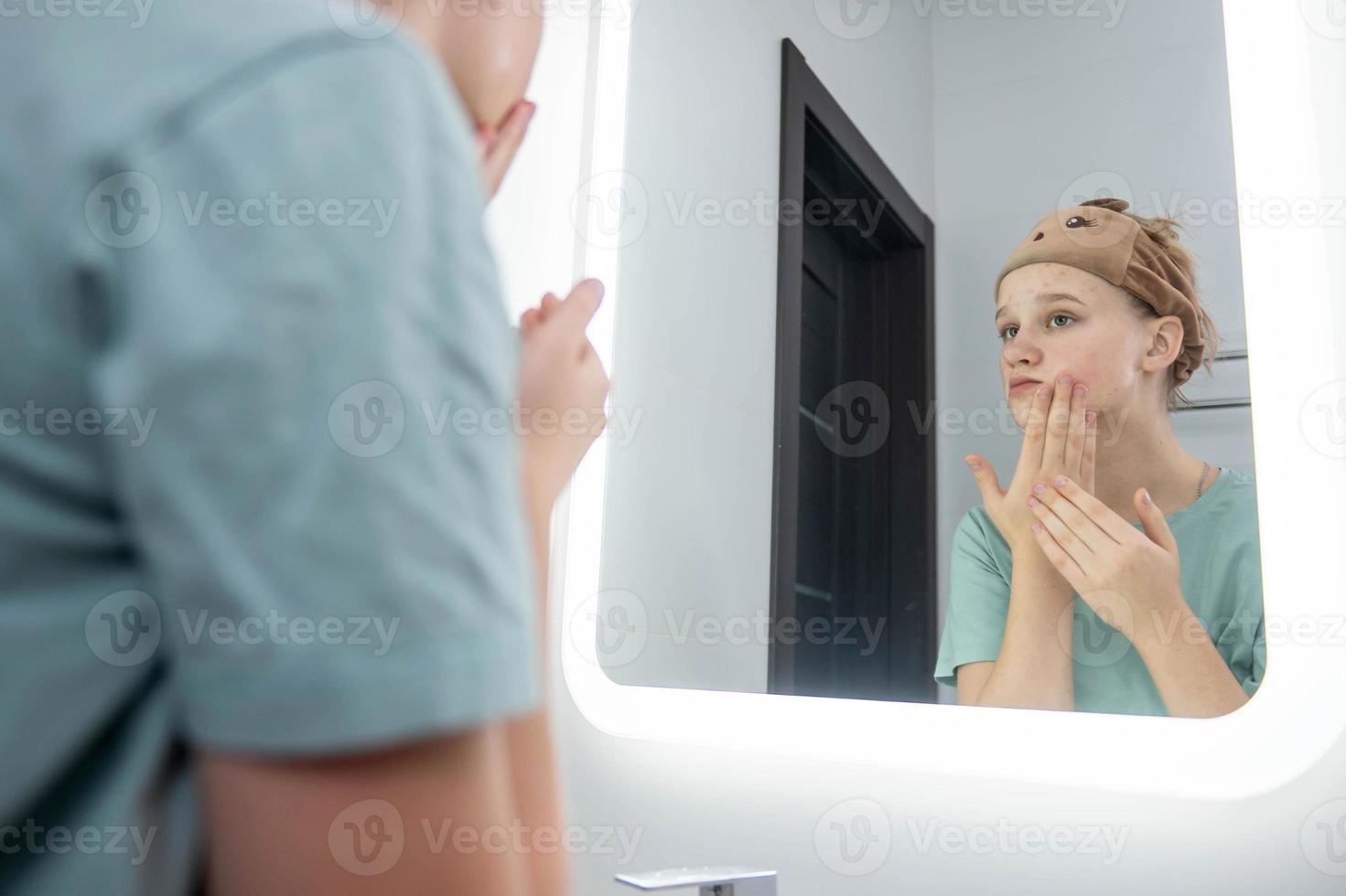 adolescente ragazza prende cura di problema pelle, sembra nel il specchio foto