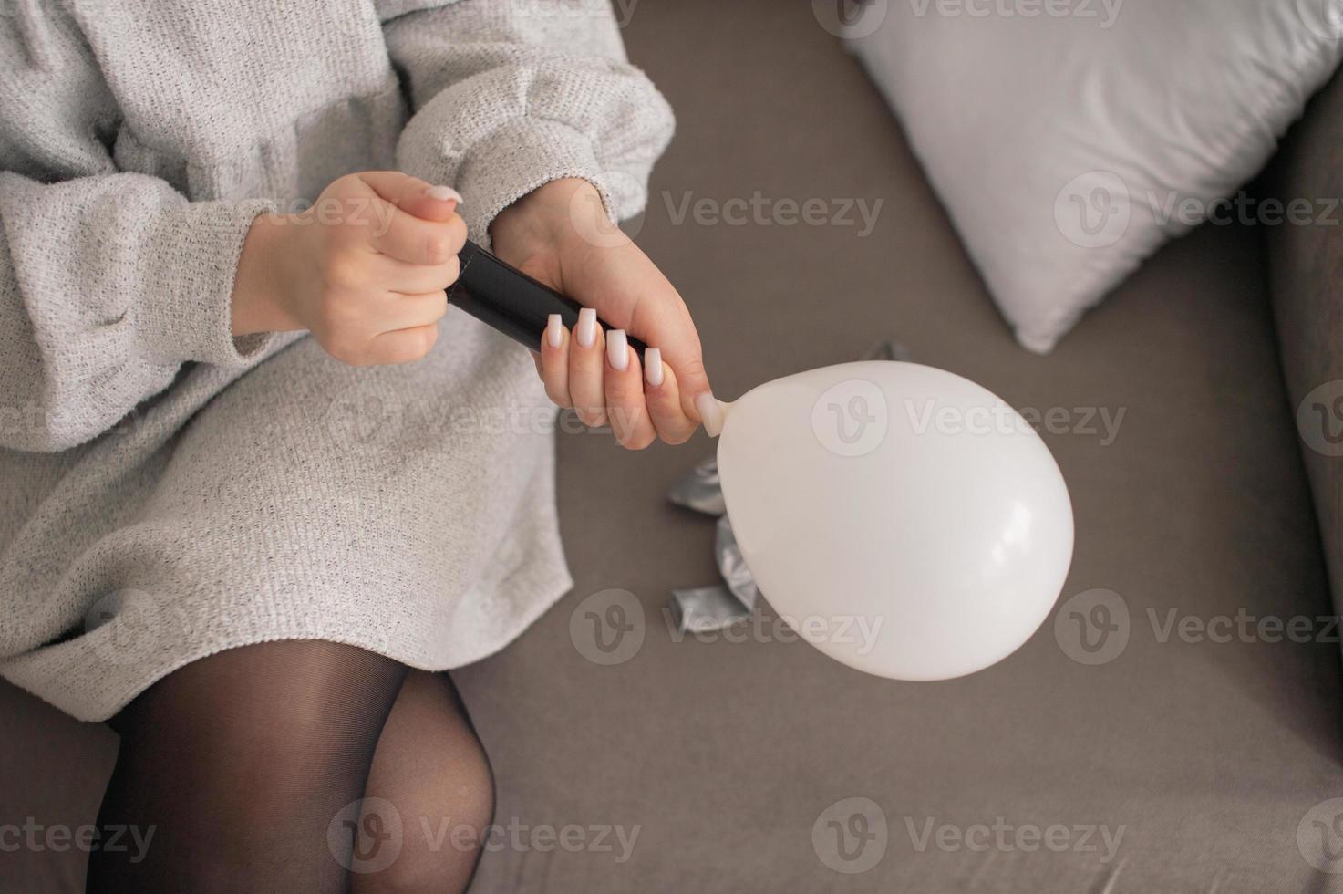 il ragazza è preparazione per il vacanza, gonfiaggio palloncini con un' pompa foto