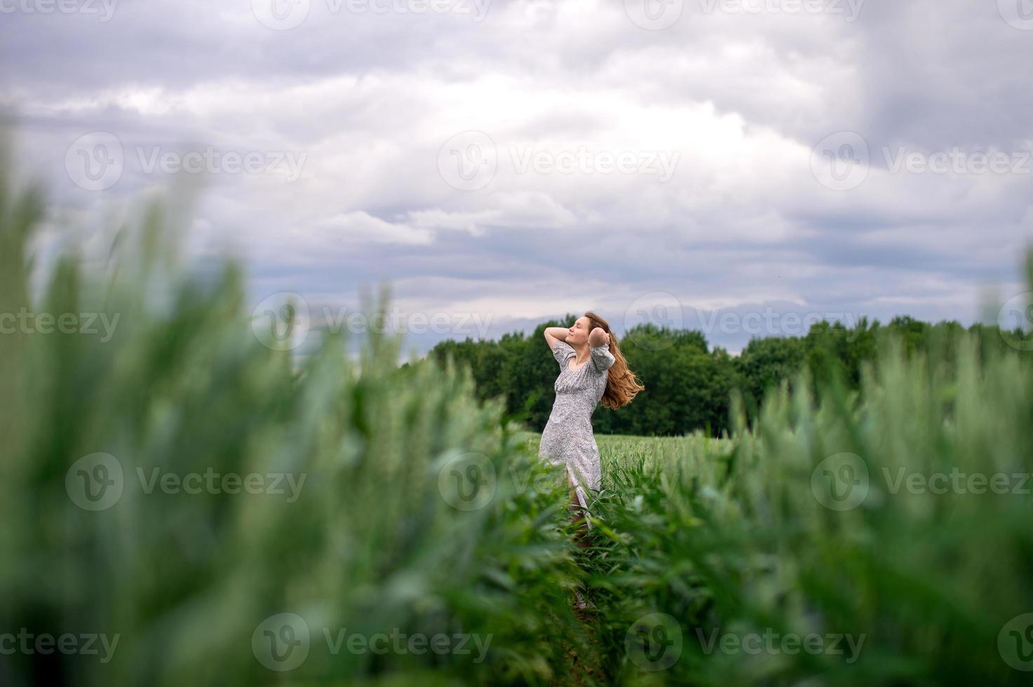 un' carino ragazza con lungo capelli nel un' vestito corre attraverso un' Grano campo foto