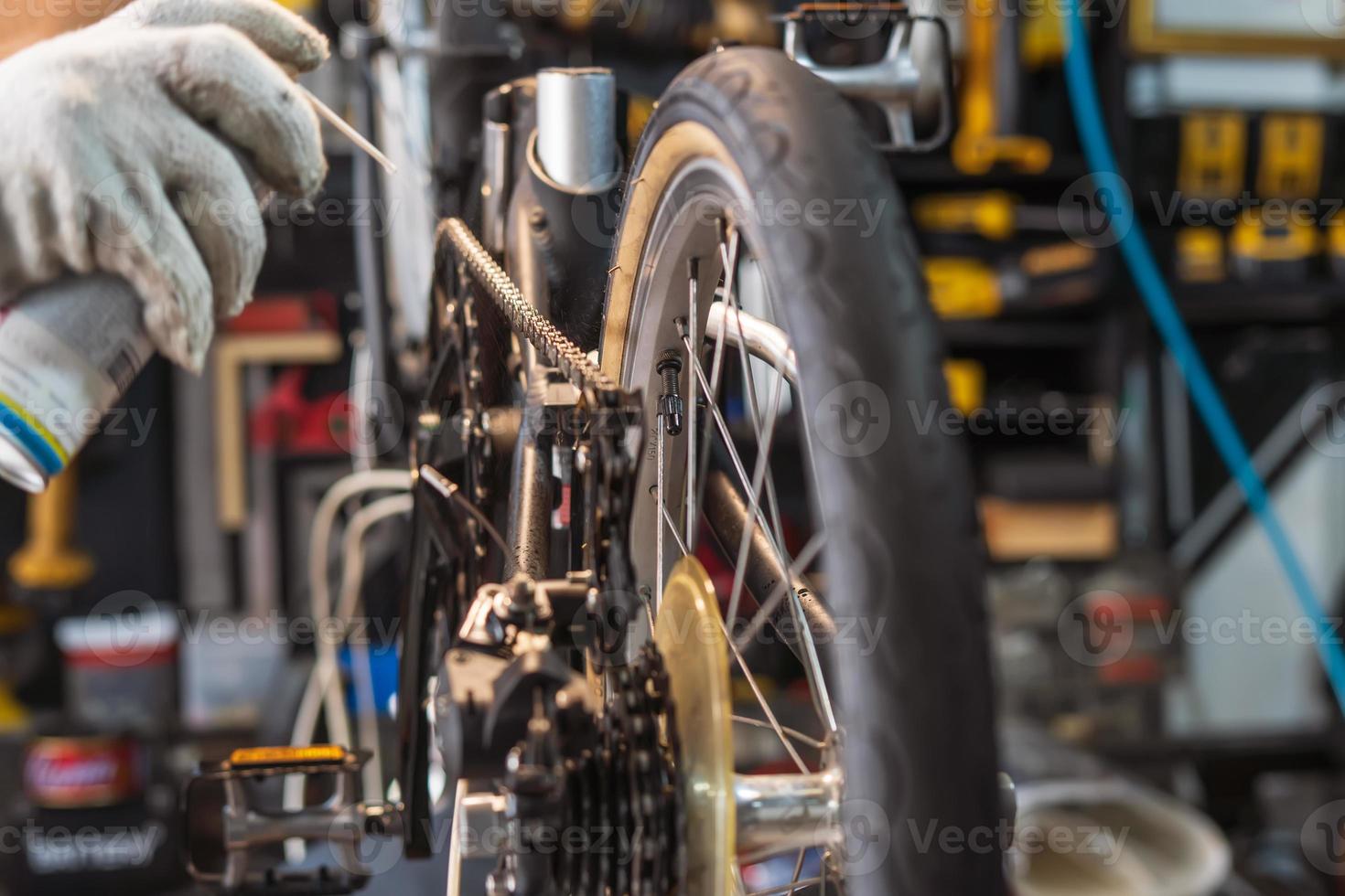 meccanico riparazione bicicletta, catena lubrificante spray per pieghevole bicicletta Lavorando nel laboratorio , bicicletta riparazione e Manutenzione concetto foto