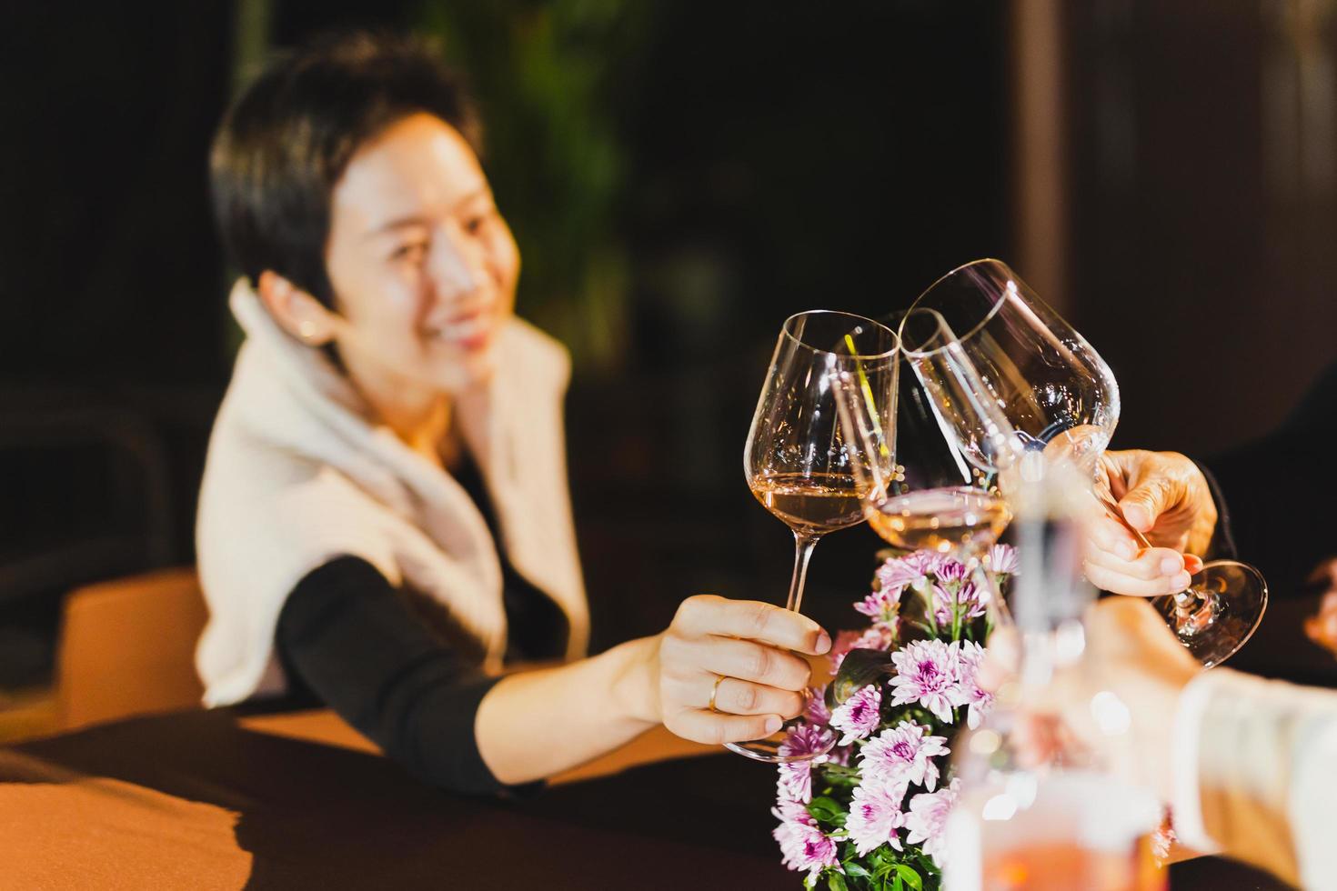 contento donna tintinnante bicchiere di vino con famiglia seduta a cena tavolo. foto