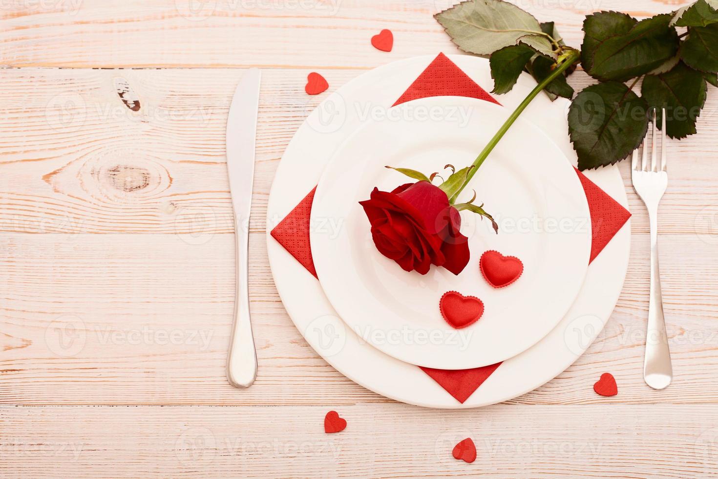 superiore Visualizza di vasellame di il giro e cuore sagomato vuoto piatto, metallo coltello e forchetta servito su bianca di legno tavolo con raggiante candela e regalo scatola preparato per celebrazione di santo San Valentino giorno foto