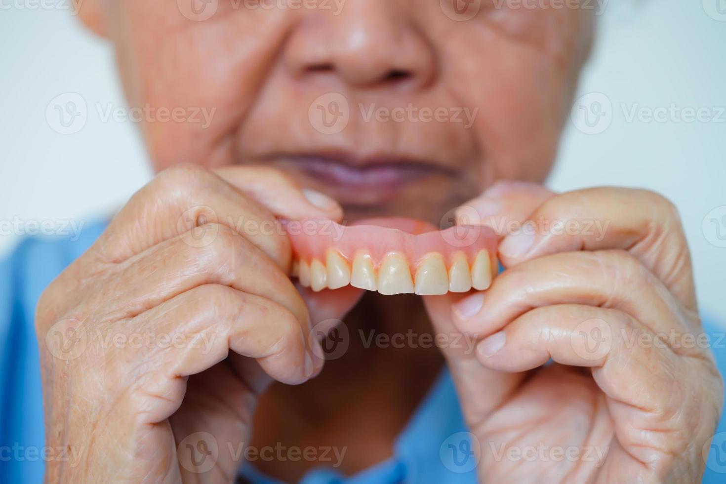 asiatico anziano donna paziente indossare denti dentiera in sua bocca per masticare cibo. foto
