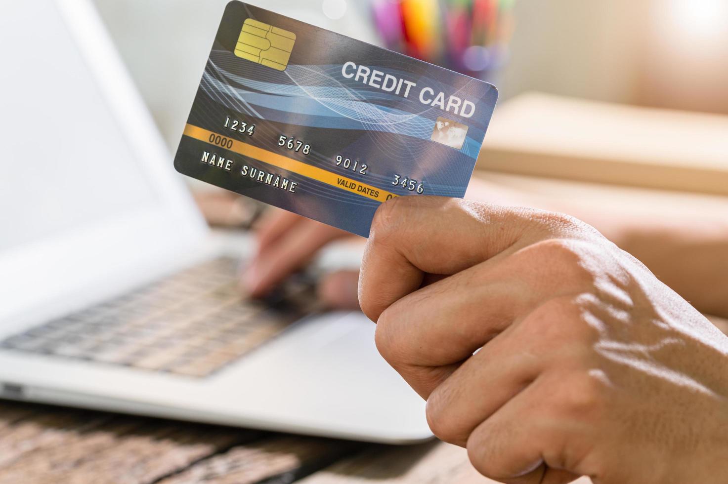 le persone usano le carte di credito per fare acquisti in linea tramite computer portatili foto