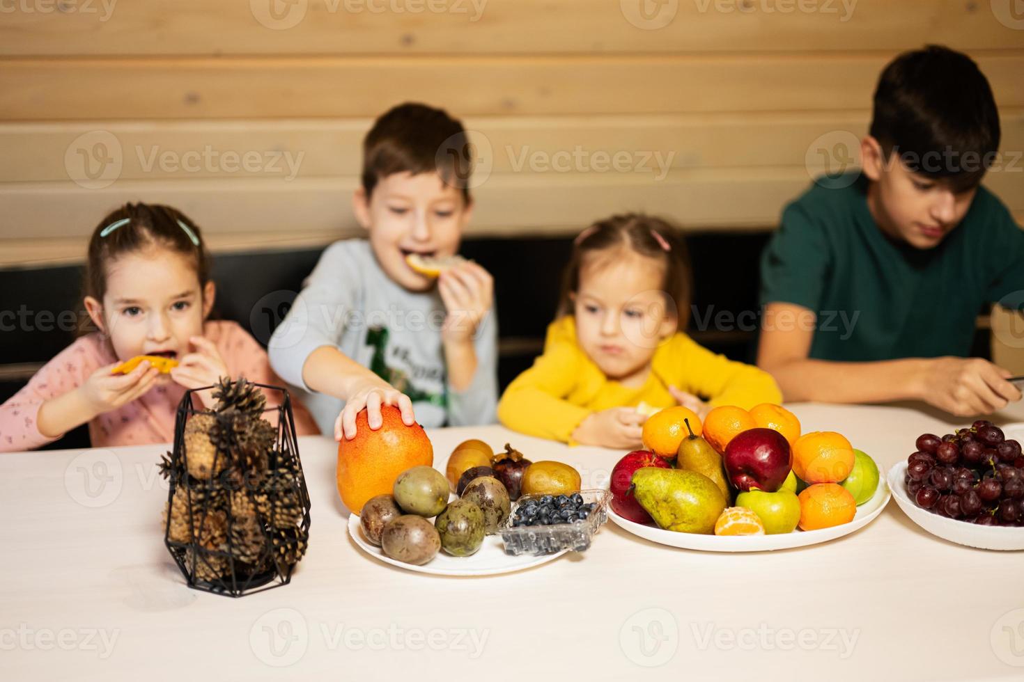 quattro bambini mangiare frutta nel di legno nazione Casa su fine settimana. foto