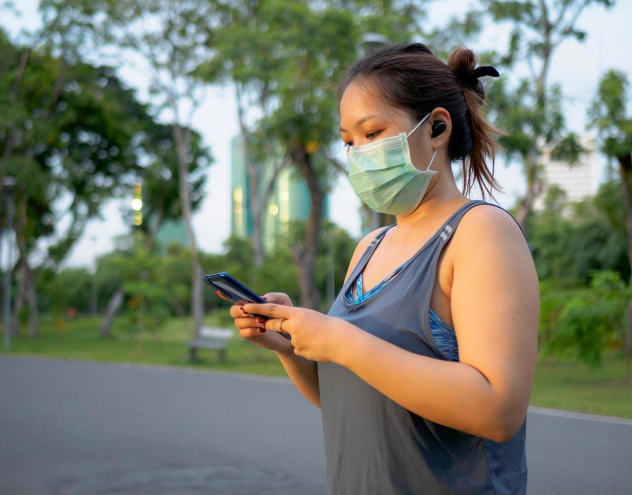 ritratto di un' bellissimo asiatico donna nel abbigliamento sportivo, in piedi con sua Indietro, allungamento prima esercizio all'aperto nel il parco nel il mattina per raggiungere un' salutare stile di vita. salutare riscaldamento su foto