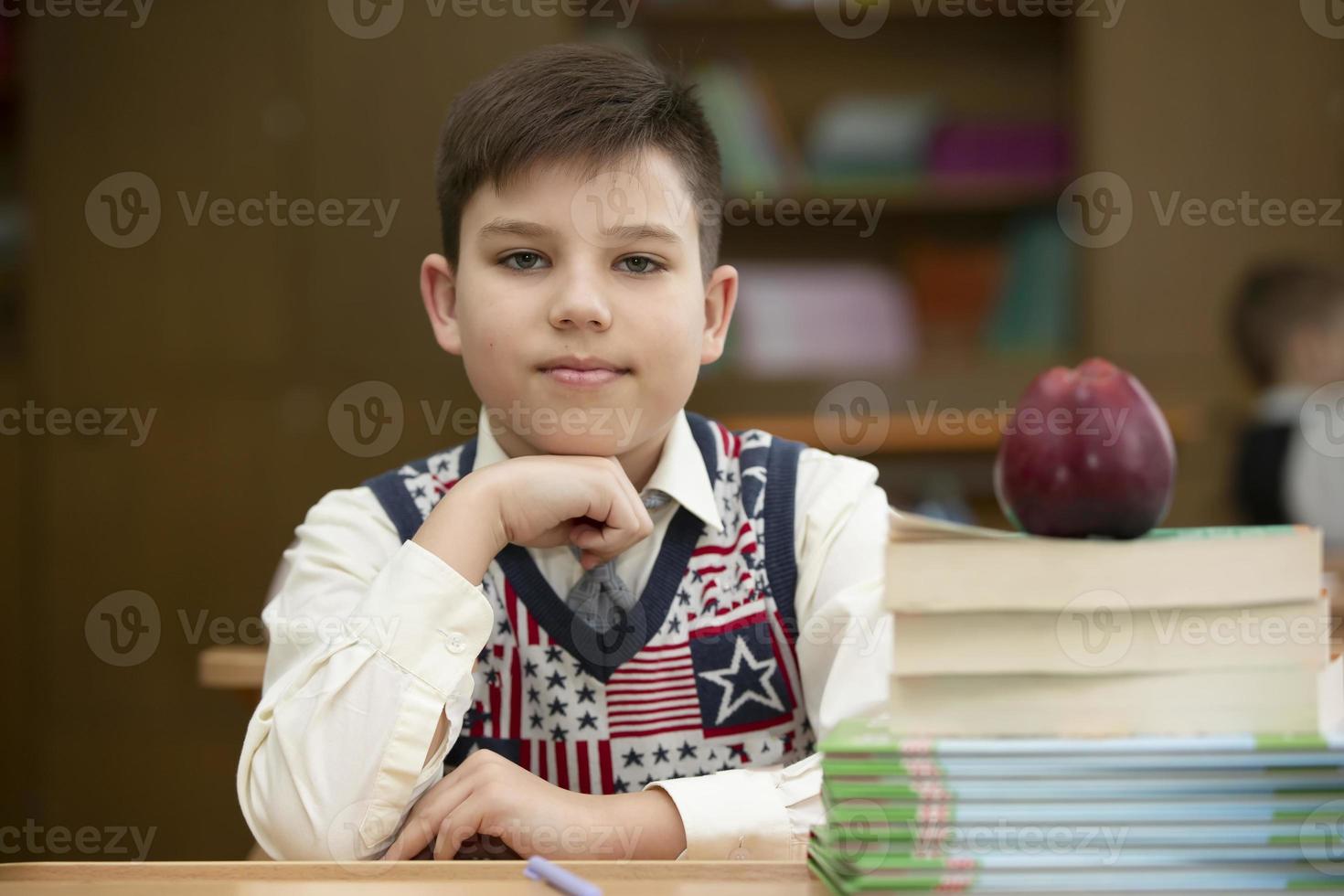 scolaro a il scrivania. ragazzo nel il aula con libri e un Mela. secondario scuola. indietro per scuola. foto