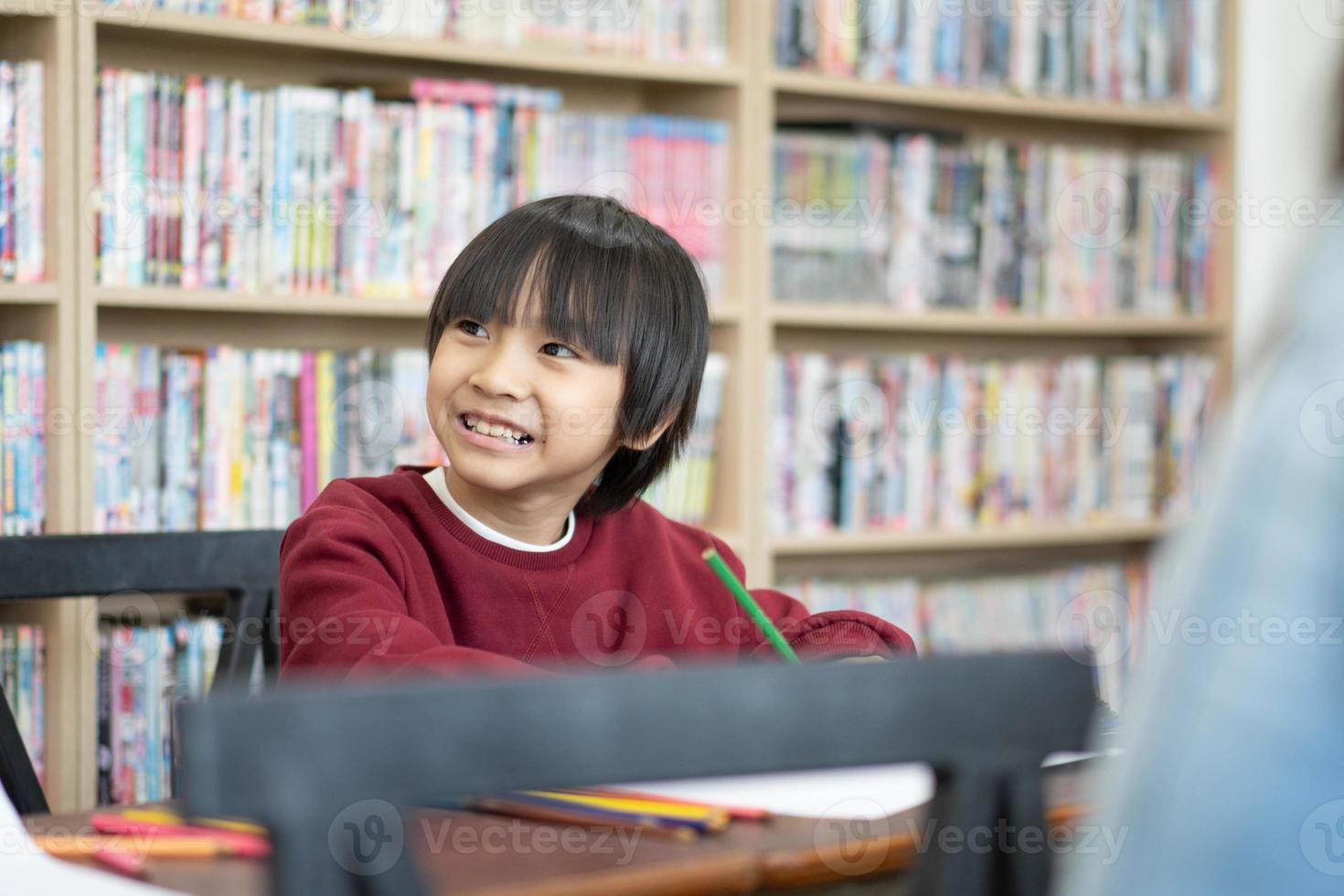 asiatico ragazzo scrittura nel taccuino, fare compiti a casa nel un' aula a scuola. formazione scolastica concetto. foto
