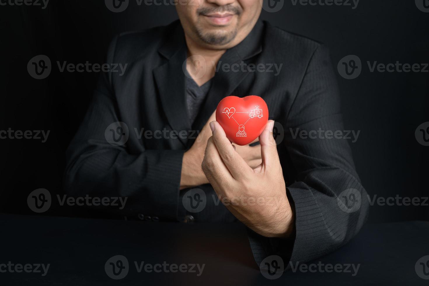 uomo Tenere rosso cuore e sentire il petto dolore su nero sfondo, foto