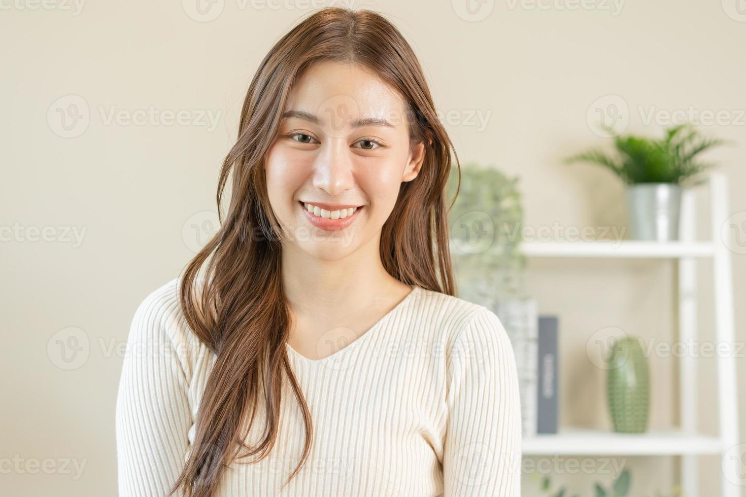 sorridente positivo, attraente asiatico giovane donna indossare casuale vestire, ritratto di bellissimo brunetta sua con lungo Marrone capelli, sensazione contento guardare per telecamera in piedi isolato su bianca sfondo. foto