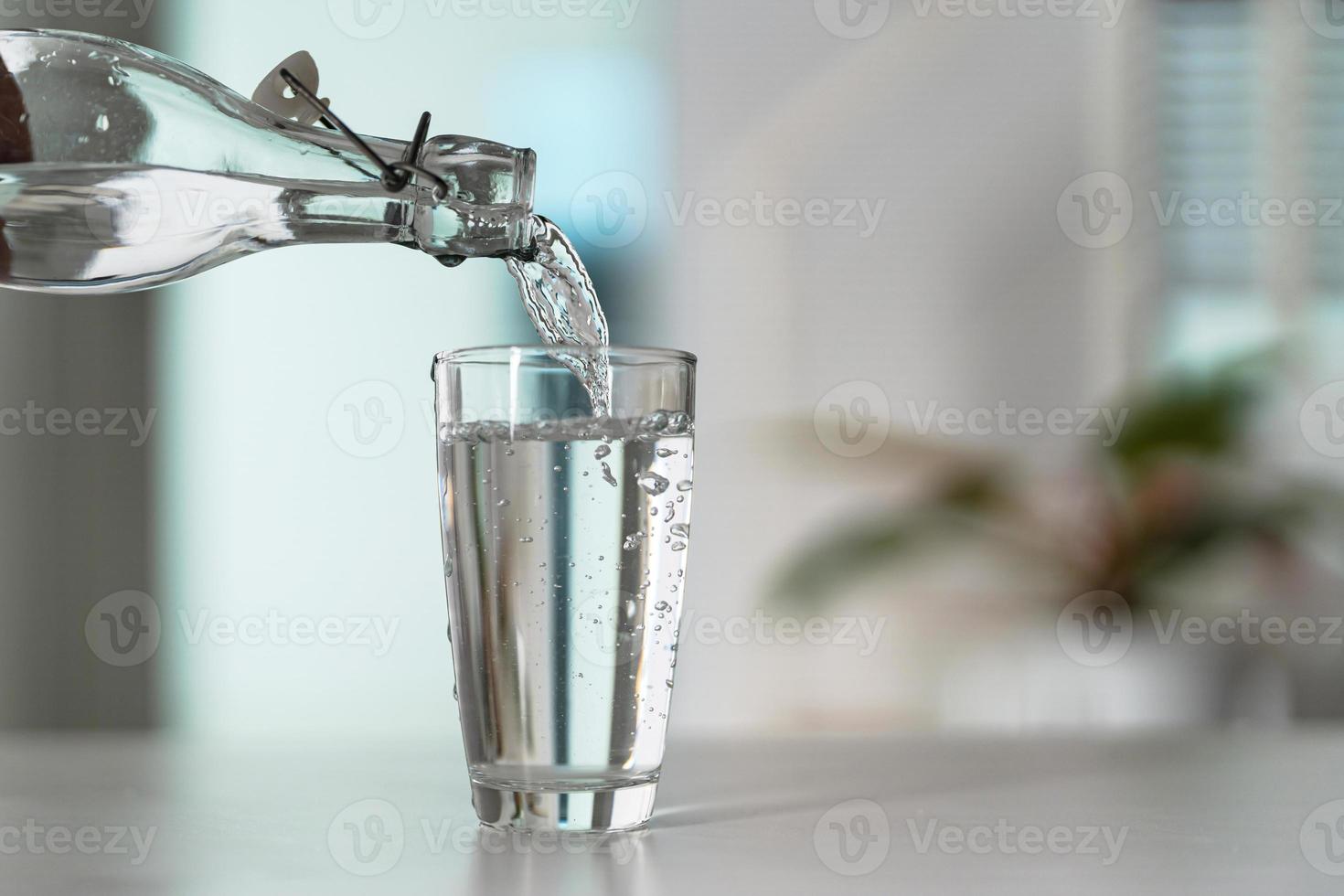 versare il acqua a partire dal il acqua bottiglia in il bicchiere foto