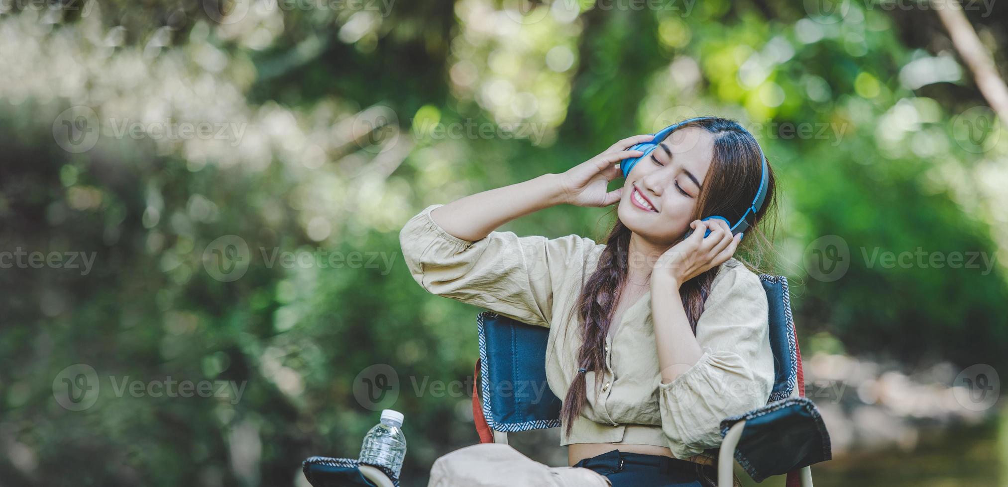 giovane asiatico donna seduta su sedia ascoltando musica a partire dal cuffie foto