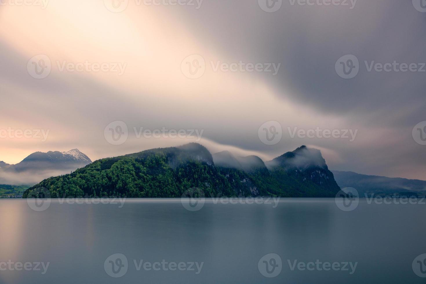 un' montagna isola su un' lago durante piovoso tempo atmosferico, nel lungo tempo esposizione foto