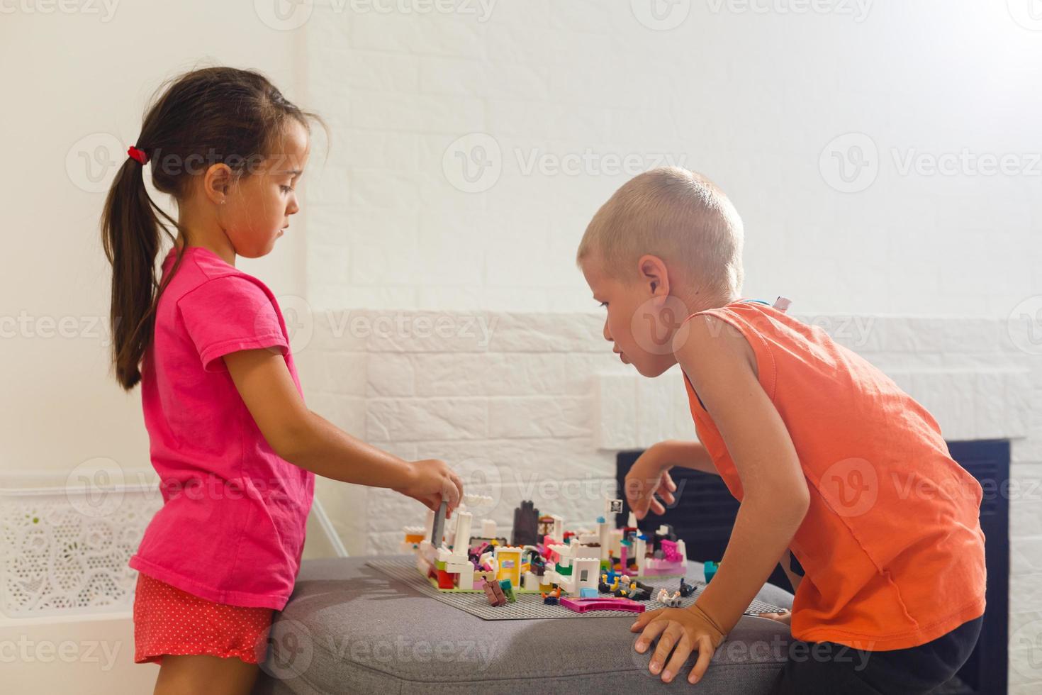 bambini giocare con un' giocattolo progettista su il pavimento di il figli di camera. Due bambini giocando con colorato blocchi. scuola materna educativo Giochi. foto