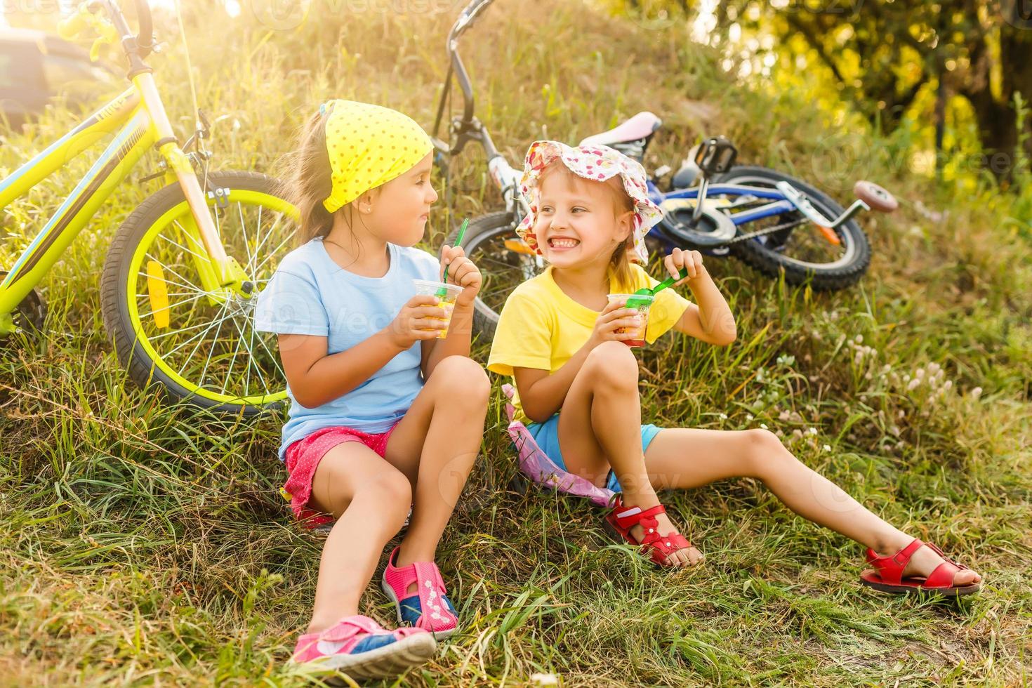 Due poco ragazze riposo bicicletta riposo nel un' parco vicino loro bicicletta foto