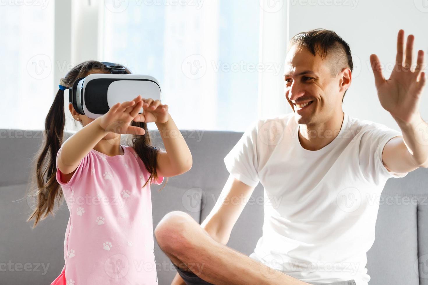 famiglia, virtuale la realtà e divertimento concetto - contento padre e poco figlia con vr bicchieri giocando video gioco a casa nel sera foto