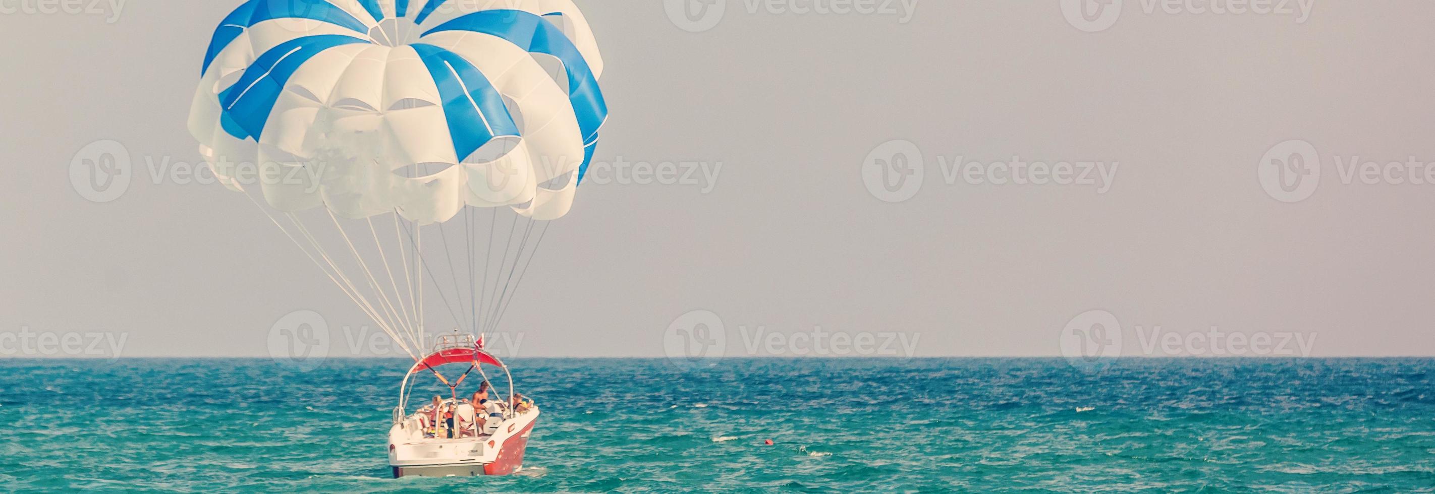 spettacolare panoramico Visualizza su il mare e blu cielo con persone volante su un' colorato paracadute rimorchiato di un' il motore barca foto