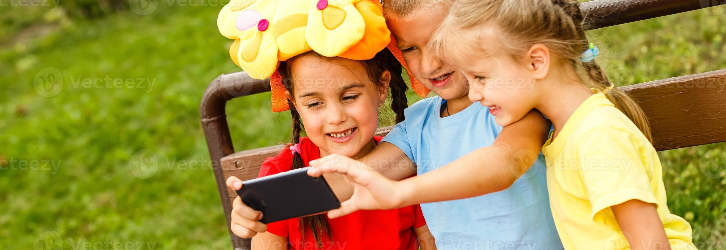 contento bambini assunzione un' autoscatto con inteligente Telefono. temi amicizia, summertine e moderno tecnologia foto