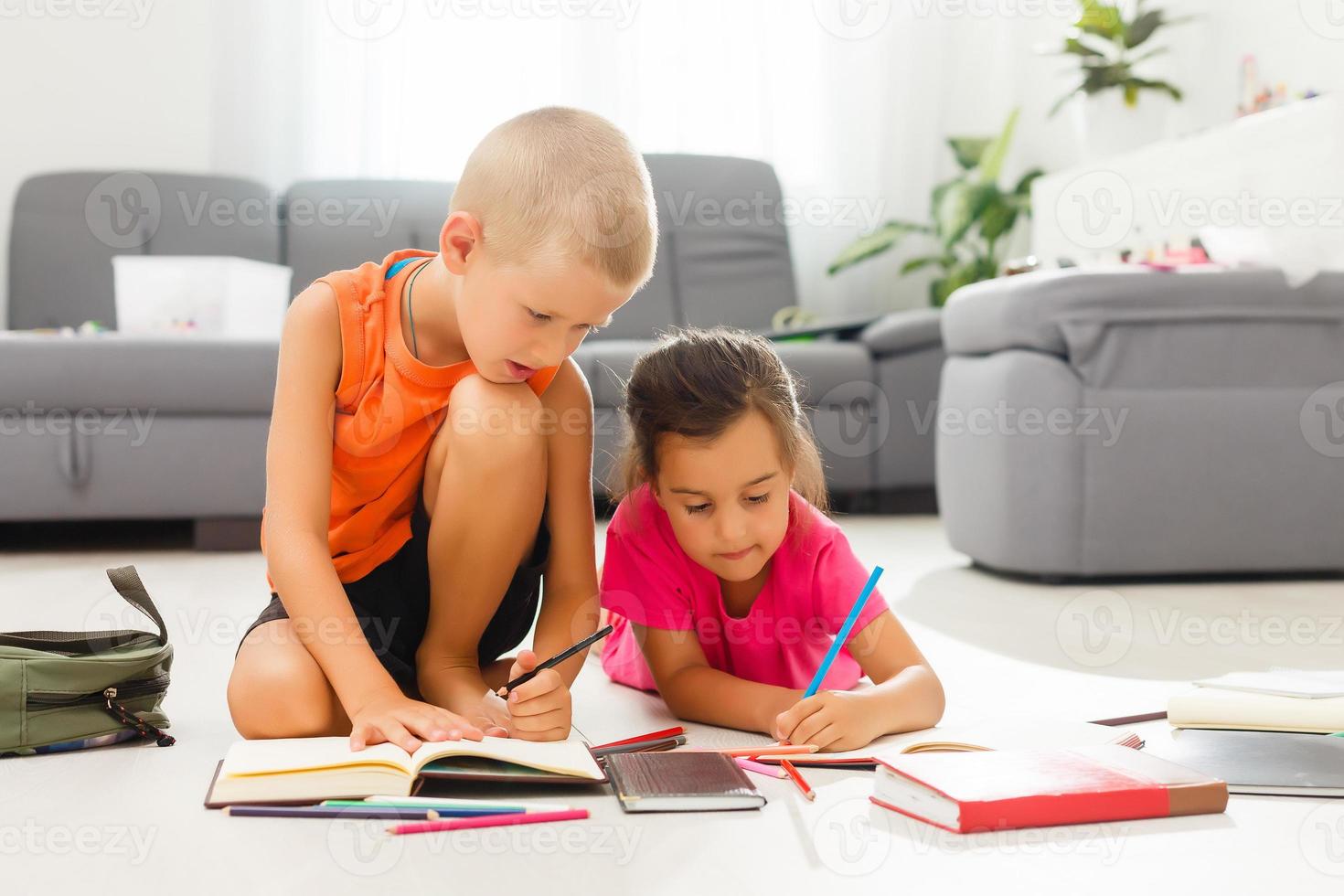 Due figli, poco ragazze di prescolastico età Guardando tavoletta a casa su il pavimento foto