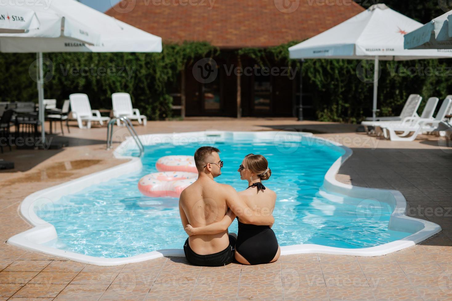 tipo e un' ragazza nel bagnarsi tute siamo rilassante, vicino il blu piscina foto